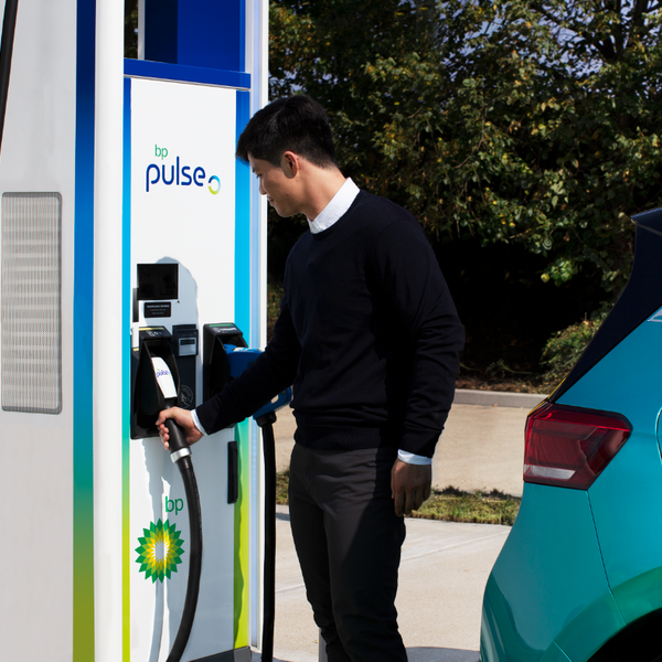 man charging electric vehicle with bp pulse fast charger